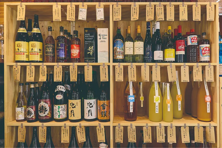 棚に並ぶ種類豊富な名酒と店主手書きの特徴を記したポップ